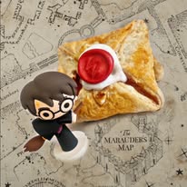 Golden pastry with white icing and a red lightning-bolt seal, beside a small Harry Potter figurine on a Marauder's Map